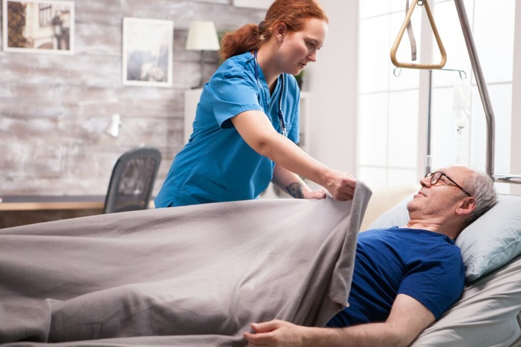 Female nurse tucking old man under the blanket